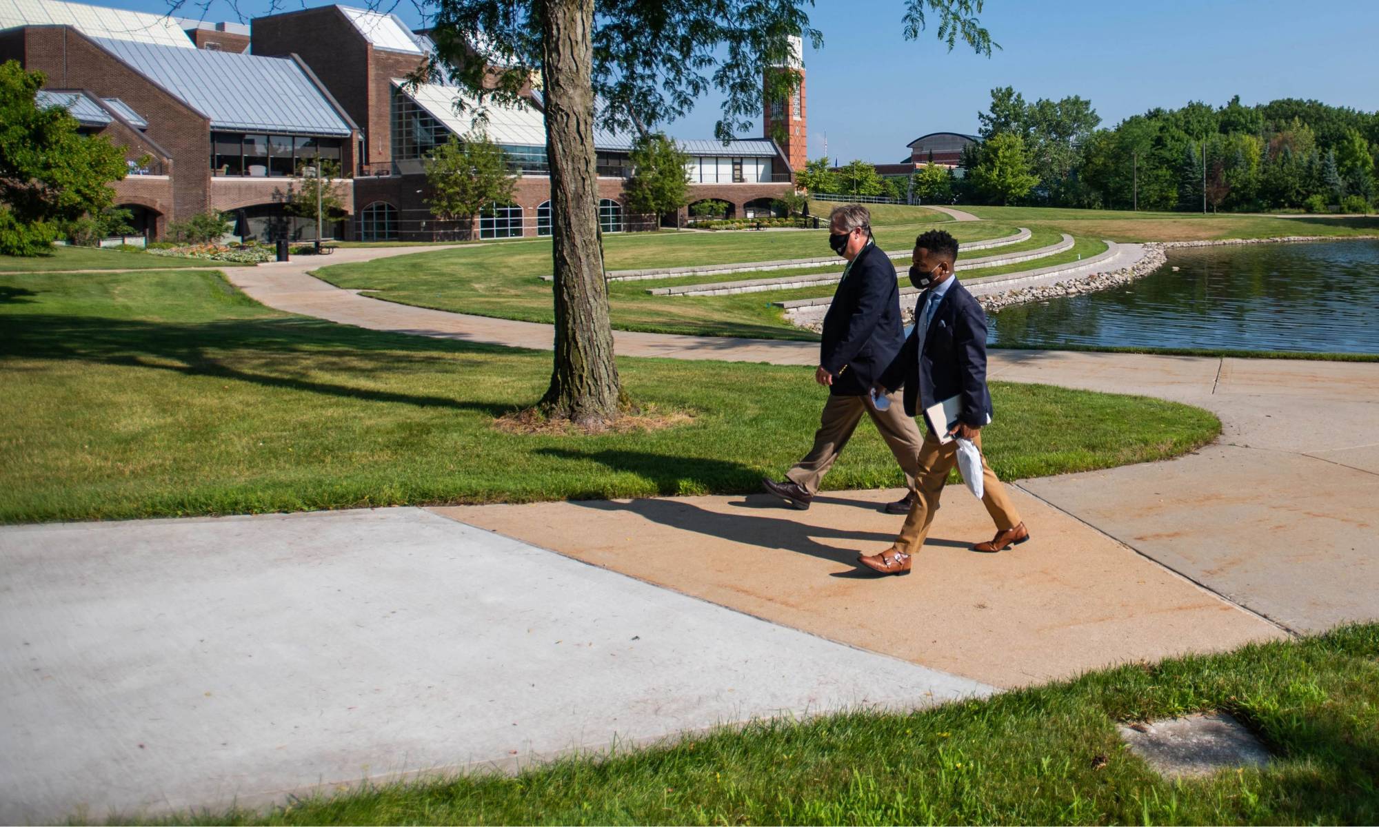 Two people walking by Zumberge Pond on GVSU Allendale Campus